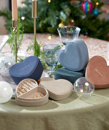 several heart-shaped jewelry boxes on Christmassy table