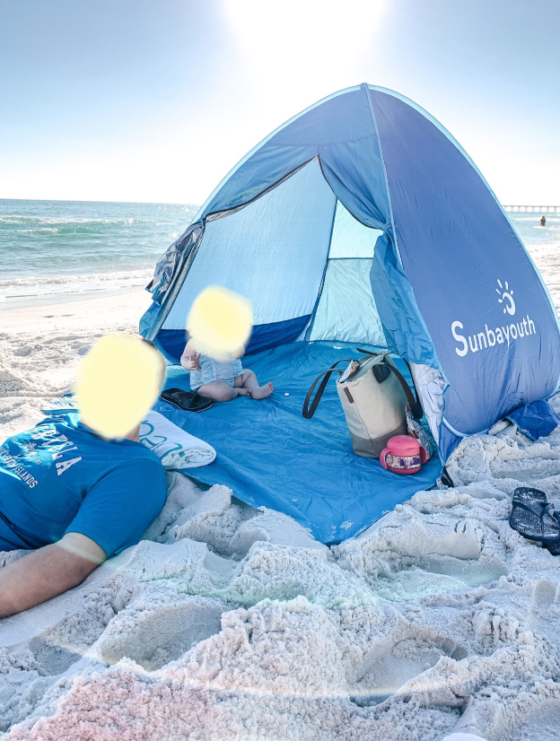 reviewer's pic of a pop up tent on the beach with a baby sitting inside