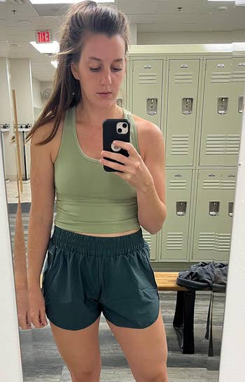 Person successful  a gym locker country   wearing an diversion  vessel  apical  and shorts, taking a reflector  selfie