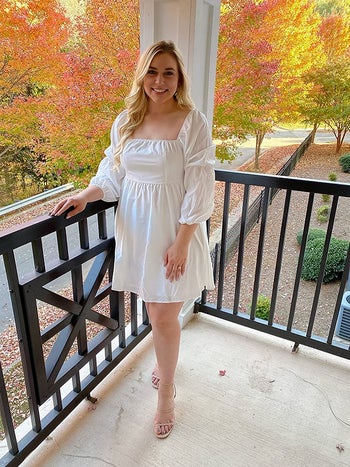 a reviewer wearing a white dress with a square neck and balloon sleeve