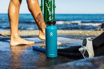 the hydro flask in blue on a beach