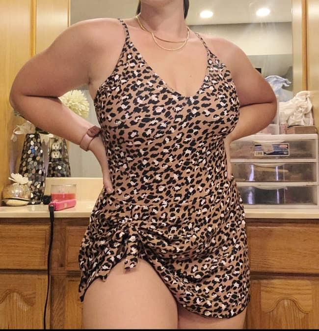 A reviewer wearing a leopard swimdress with an asymmetrical hem 