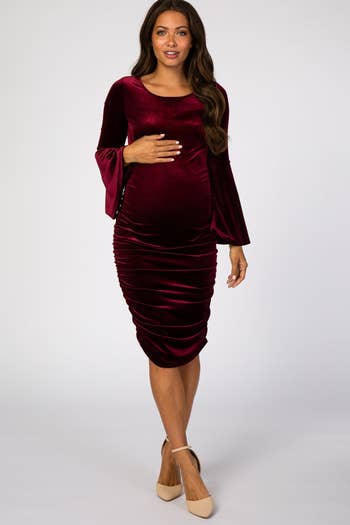model posing in burgundy velvet dress with bell sleeves
