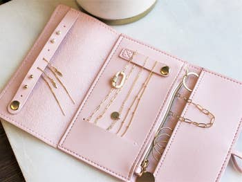 pink foldable jewelry organizer with gold baubles inside
