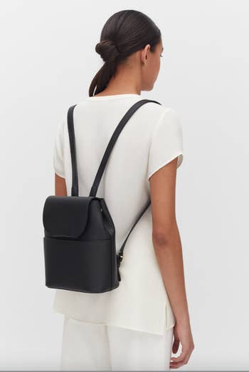 model wearing black leather mini backpack