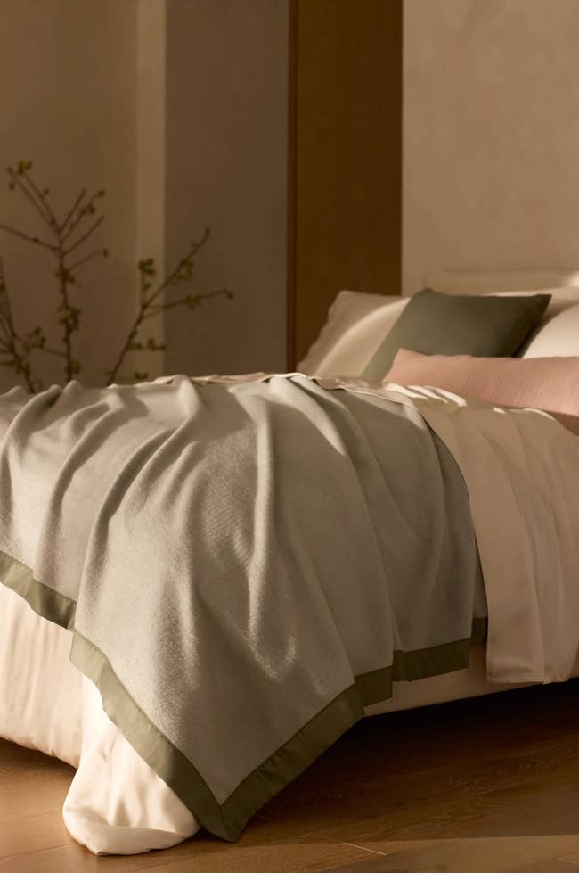 Cozy bedroom scene with a neatly made bed featuring layered blankets and pillows, suggesting a warm and inviting atmosphere