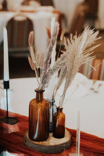 Elegant dried pampas grass in glass vases on a table with minimalist decor, suggesting a chic, natural aesthetic for home shopping
