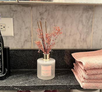 pink reed diffuser with flowers in reviewer's bathroom