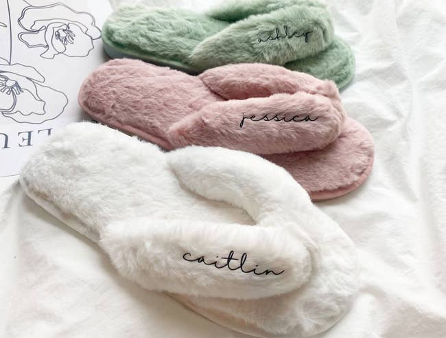 Three furry slippers in white, pink, and green and personalized with different names