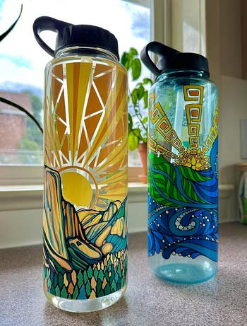 reviewer photo of two 48-oz water bottles with artistic designs
