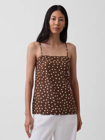 A idiosyncratic wears a brownish polka dot cami apical and achromatic pants, showcasing a casual manner benignant perfect for shopping