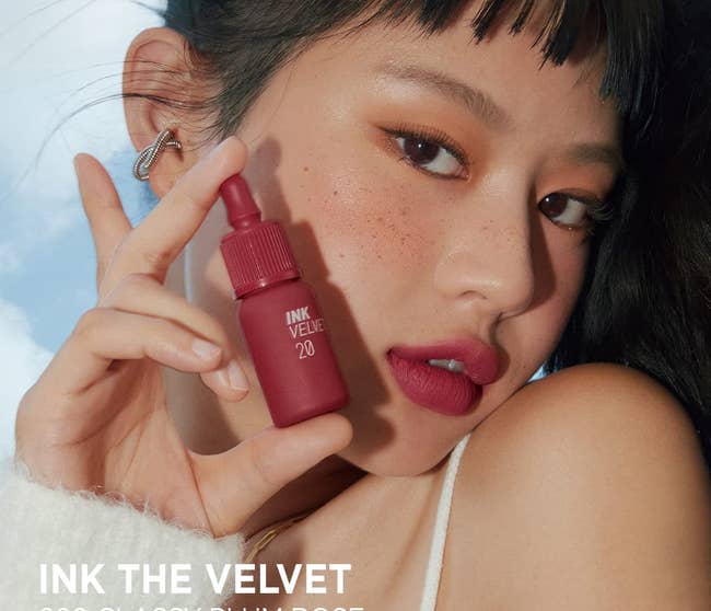 model wearing shade 'classy plum rose' and holding up lip tint bottles