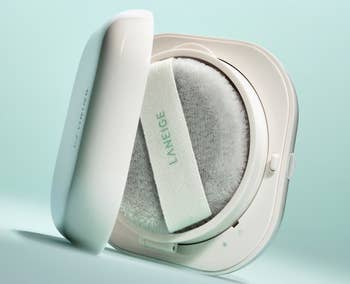 A Laneige cushion compact with an unfastened lawsuit showing a brushed applicator puff and its marque name