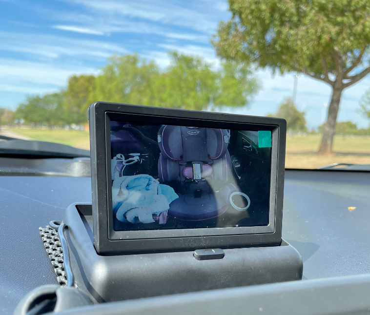 Backup camera screen showing an empty car seat inside a vehicle, parked outdoors