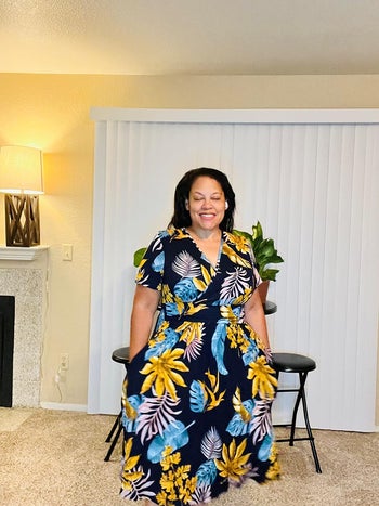 Lady in a floral wrap dress standing indoors, smiling. Moral for a dress attempting handbook