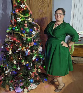 reviewer in the green dress standing next to a christmas tree