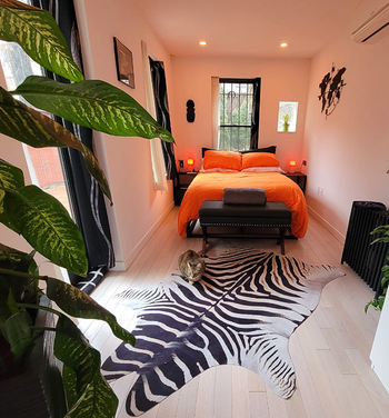 zebra rug displayed on floor at an angle in reviewer's small apartment bedroom