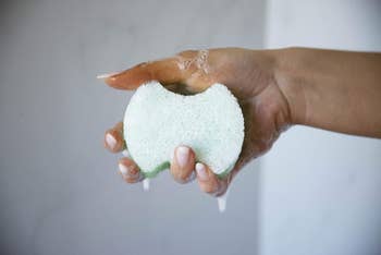 Model holding foot soap with loofah side facing outward