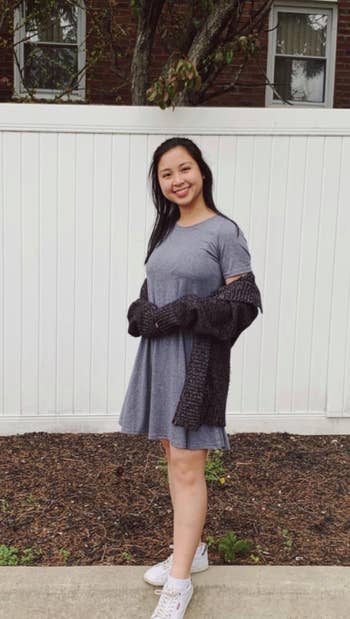 reviewer wears gray T-shirt dress with a black cardigan