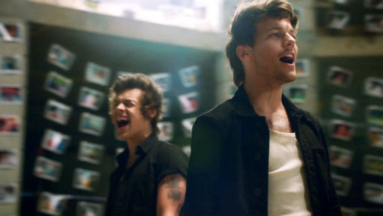 Harry and Louis sing as polaroid pictures hang behind them in the "story of my life" video