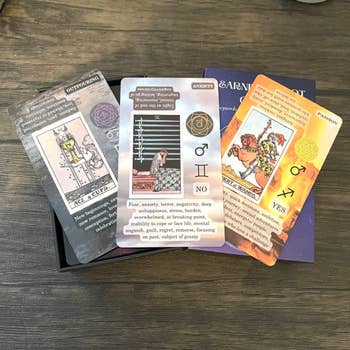 Assorted tarot cards spread out on a wooden surface, focusing on their designs and text descriptions
