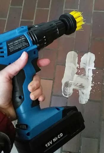 reviewer holding a cordless drill with a brush attachment, cleaning a brick surface
