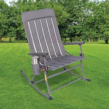 Foldable outdoor chair with armrests and cup holder, set on grass