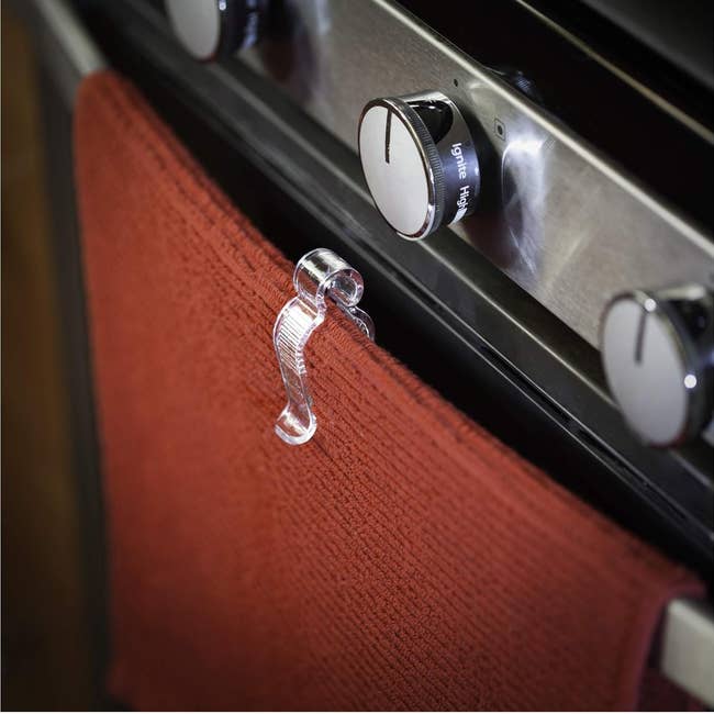 Close-up of a glass oven knob holder with a red towel hanging on it