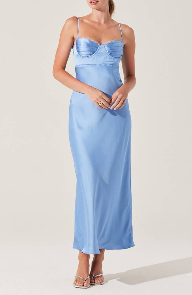 Person wearing an elegant satin slip dress with spaghetti straps, holding hands lightly. Suitable for formal events or stylish occasions