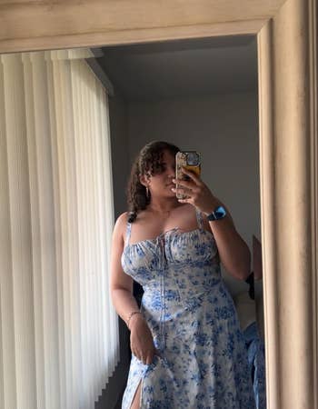 reviewer in a mirror selfie wearing a floral dress with a slit, ideal for a summer wardrobe update
