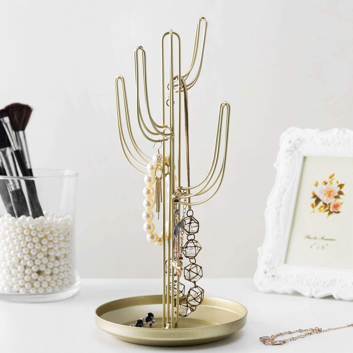 the gold cactus jewelry stand holding earrings and necklaces