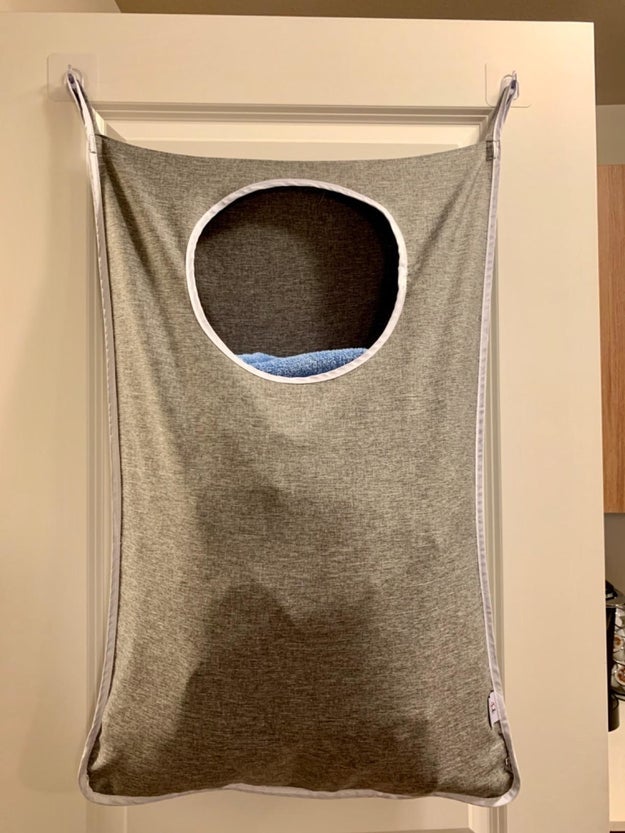 Reviewer photo of the laundry hamper hanging over top of door filled with laundry