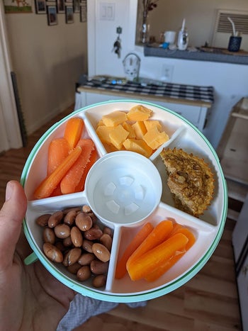 A reviewer's open container with a different snack in each compartment