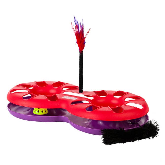 A red and purple contraption with a feather attachment at the side and yellow balls in the middle