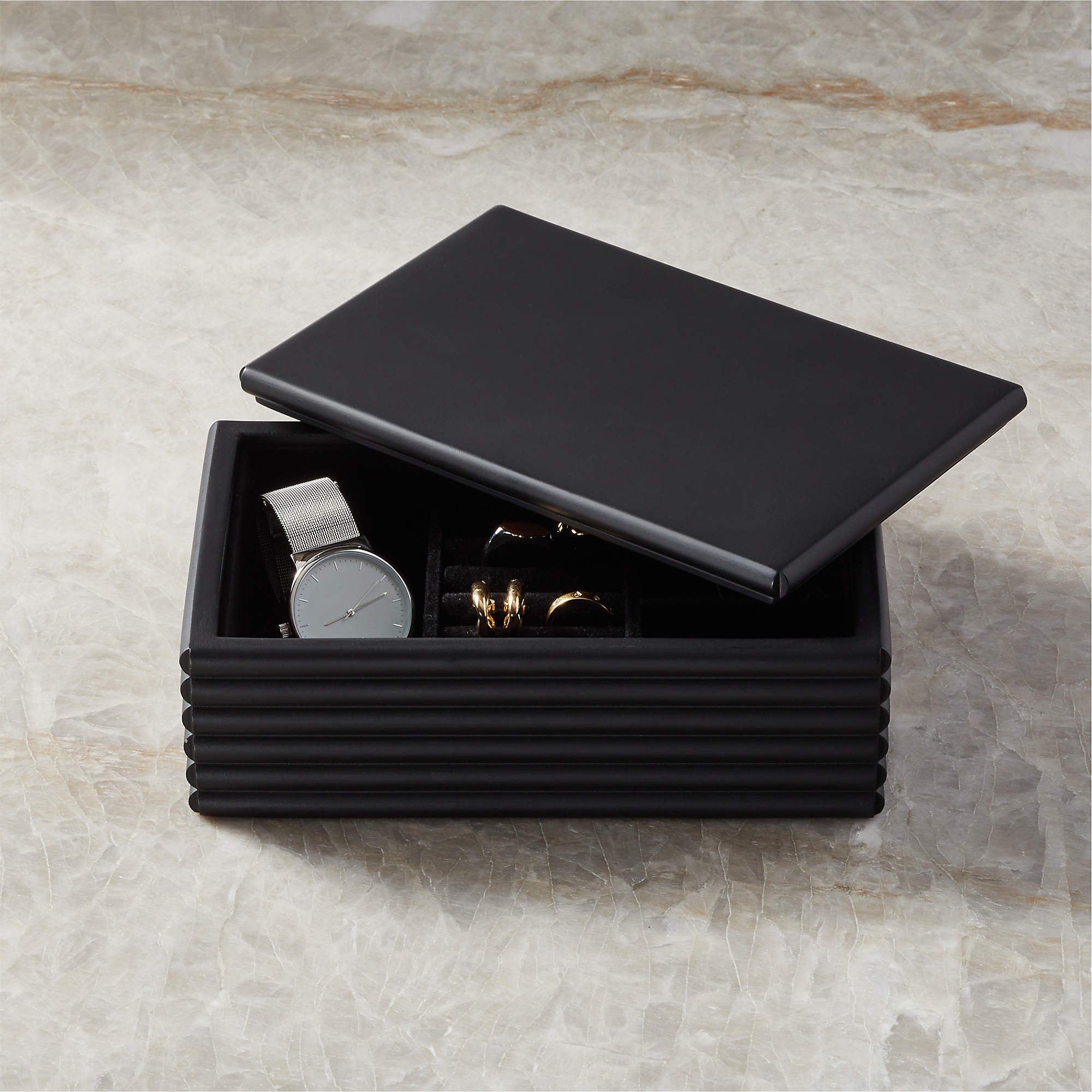 black lidded jewelry box with watch and rings inside