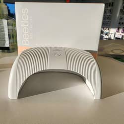 Beetles Gel Polish UV nail lamp with sleek, curved design, displayed on a table