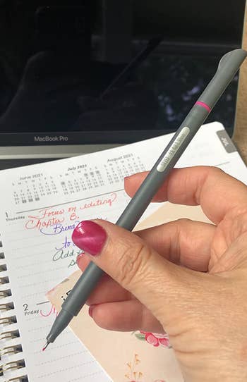 a reviewer holding up the pen and showing the fine tip