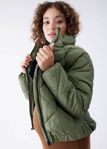model wearing an expandable green puffer coat
