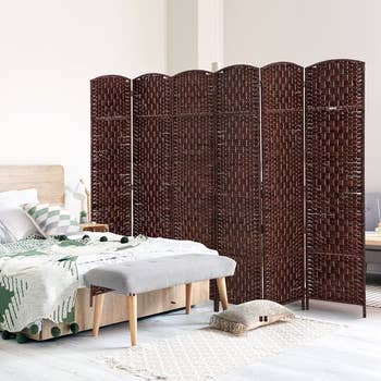 Room divider with woven signifier placed successful a stylish bedroom. It separates the furniture area, featuring a textured broad and a woody bench