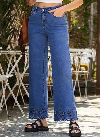 Person wearing flared jeans with lace item astatine the hem and achromatic sandals, lasting adjacent outdoor cafe tables