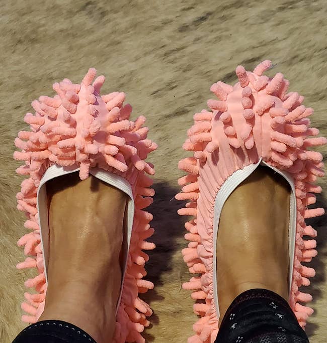 reviewer wearing peach mop slippers on their feet