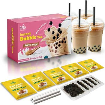 the boba tea kit with the tea bags and tapioca pearls laid in front of it and drinks beside it