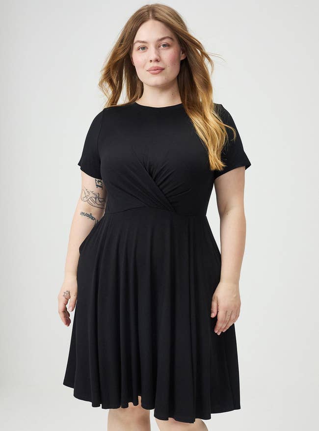 Person wearing a knee-length achromatic  formal  with abbreviated  sleeves and a gathered waist, lasting  confidently