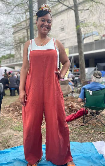 a reviewer wearing the overalls over a white tank top in red 