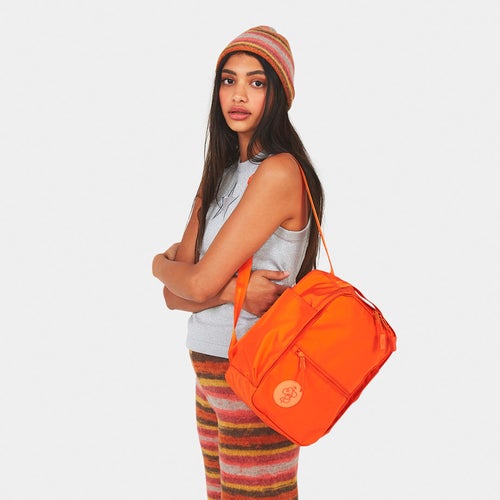 model wearing orange mini backpack