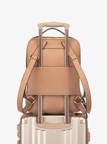 Tan leather backpack attached to a suitcase handle, showcasing travel-ready luggage for convenient buying  and transport