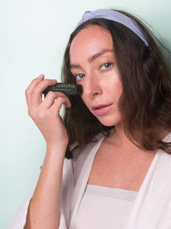 model applying the matcha stick to their face