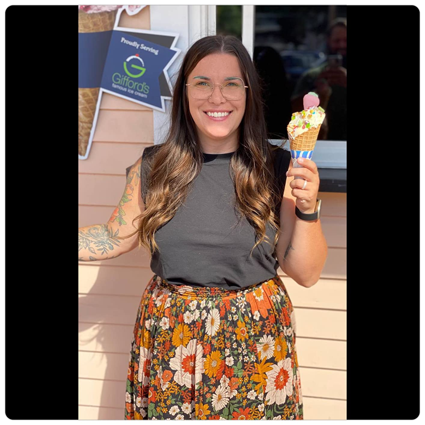 Person smiling and holding an crystal  pick  cone, wearing a achromatic  apical  and floral skirt