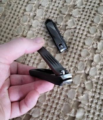 reviewer holding a black nail clipper 
