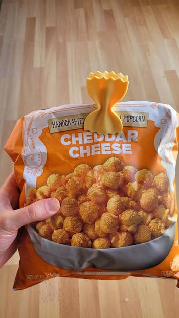 Hand holding a container  of handcrafted popcorn labeled 
